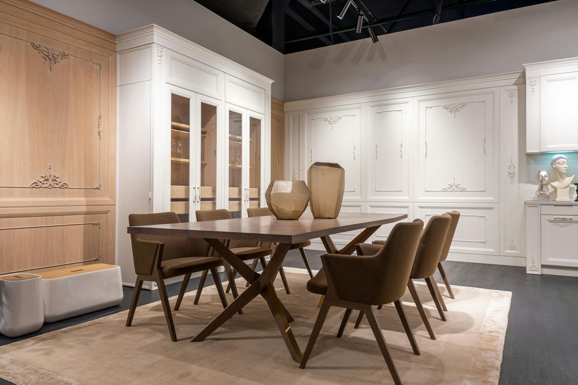 Modern stylish dining room with white cupboards and decorative vases on dining table in contemporary apartment