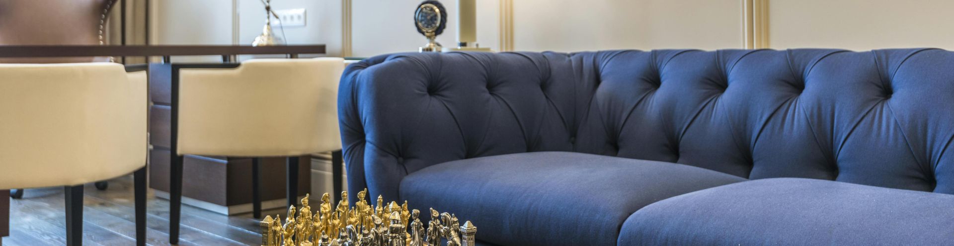 Stylish living room featuring a blue couch, chess set, lamps, and modern decor.